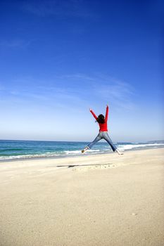 Young woman jumping on the beach and having fun