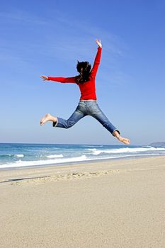 Young woman jumping on the beach and having fun