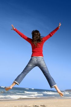 Young woman jumping on the beach and having fun