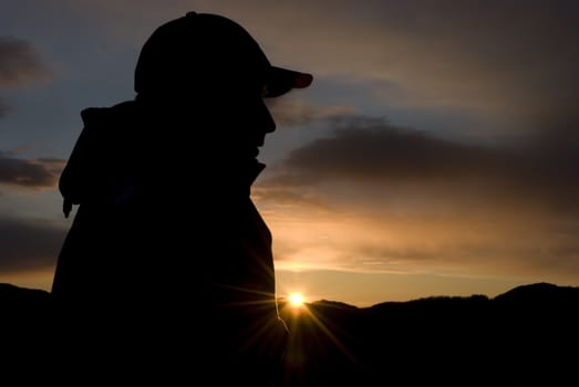 Male person sitting in the mountain under sunset!