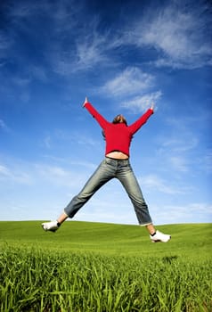 Woman making a big jump on a beautiful green meadow