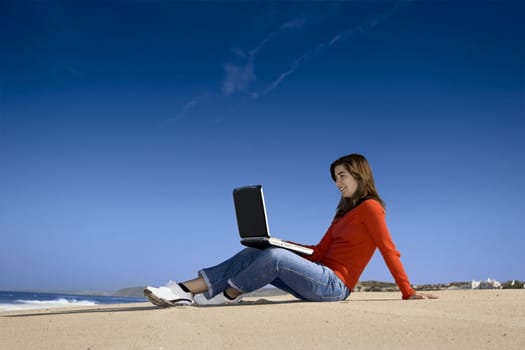 Woman working with a laptop on the beach