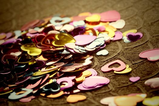 metallic confetti hearts on brown background
