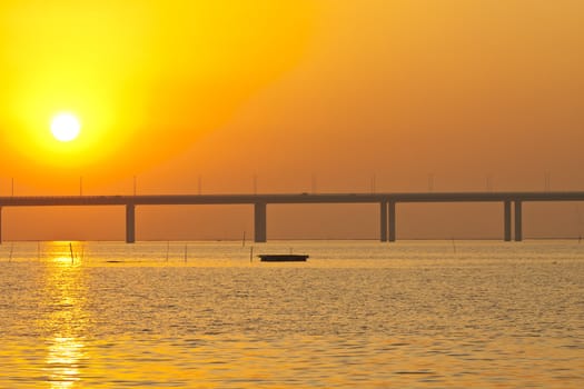 Sunset over a bridge with moving boats