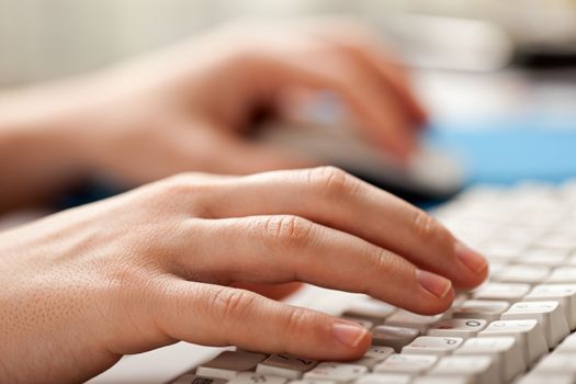 Human hand holding mouse typing computer keyboard