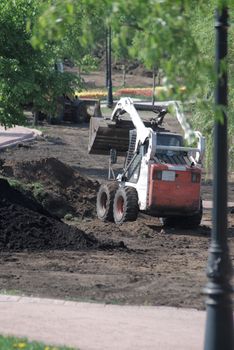 mini wheel excavator working in city park at the spring