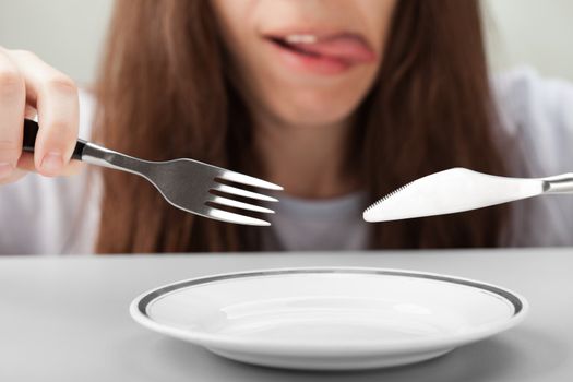 Hungry person hand holding fork knife on food plate