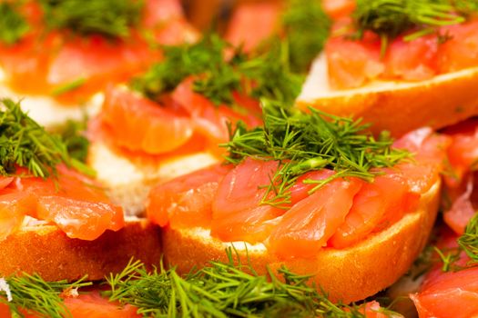 A heap of sandwiches with red fish meat and green parsley