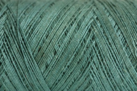 Macro view of reel of green thread. Green background