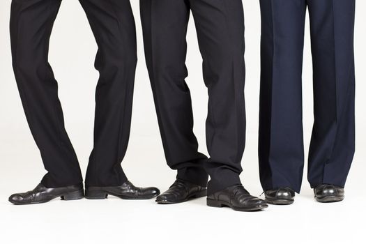 Three businessmen legs over white background doing funny poses.