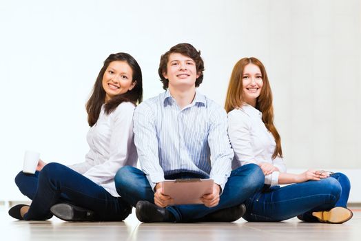 portrait of a group of young people sitting on the floor, man and two attractive women