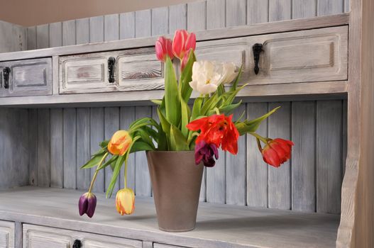 Tulips on an old fashioned bookshelf in shabby chic.