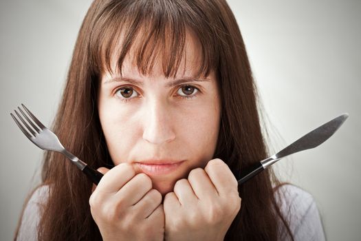 Hungry woman hand holding fork and knife