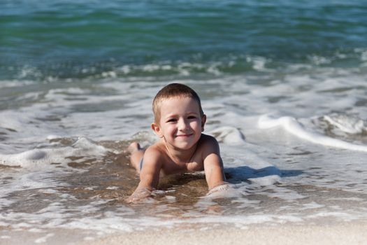 Summer vacations - little smiling child boy playing on sea sand beach