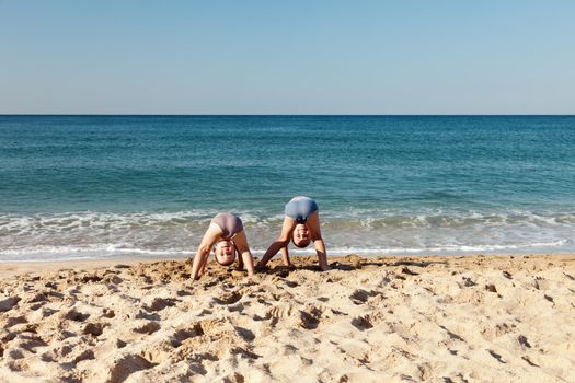 Summer vacations - two little child boy brothers playing on blue sea sand beach