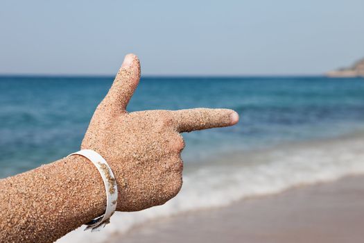 Summer vacations - woman hand index finger pointing direction to sea sand beach