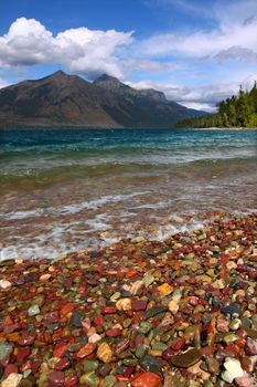 Small waves trickle through bright glacial rocks of Lake McDonald in Glacier National Park.