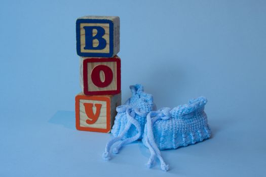 Blue booties and baby bloxks spell out Boy.