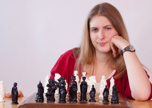 Pretty woman in red playing chess.