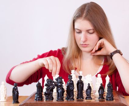 Pretty woman in red playing chess.