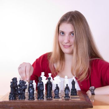 Pretty woman in red smiling and playing chess.