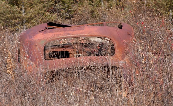 Old abandoned car in a field near a ghost town.