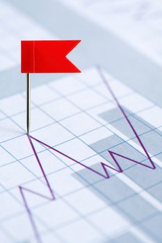 Business concept. Red flag thumbtack on paper background with business chart