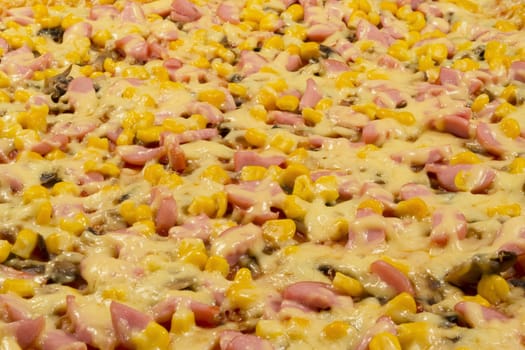 Large pizza closeup with cheese, sausage, corn and mushrooms, side view.