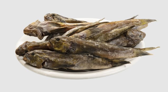 Dried gobies on a white plate close-up. Isolated on a light gray background.