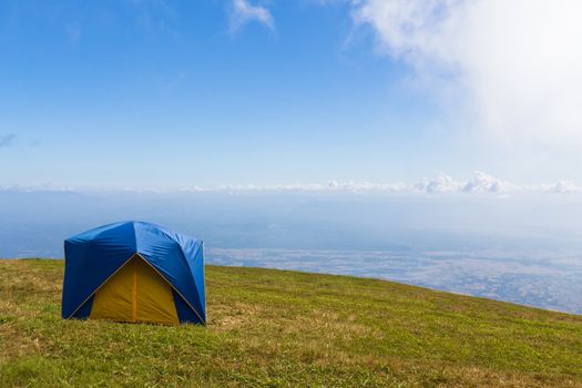 Tent on a grass under white clouds and blue sky