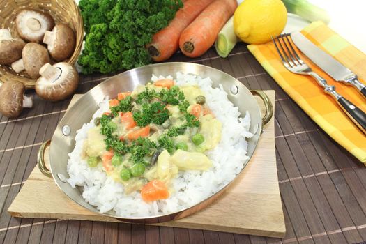 chicken frikassee with rice, vegetables and parsley in a pan