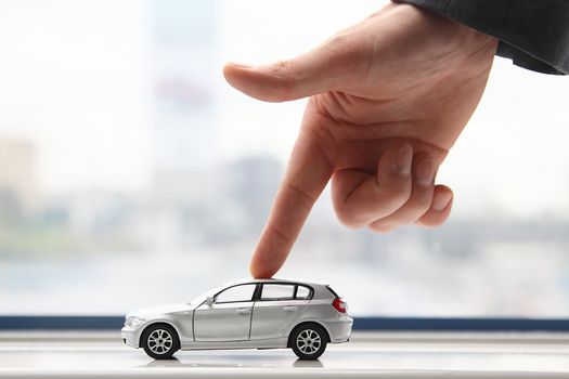 The finger of the businessman moves the toy car