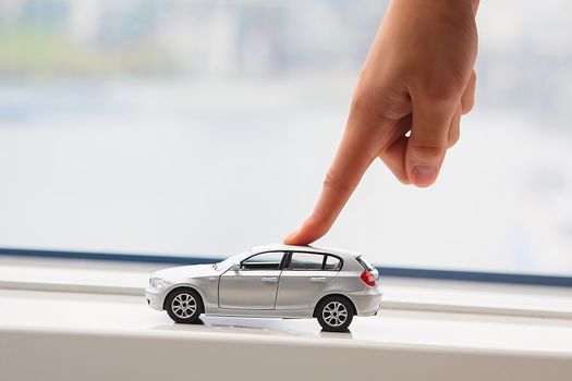 The finger of the businessman moves the toy car