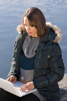 Woman sits on the lake and surf the internet with laptop