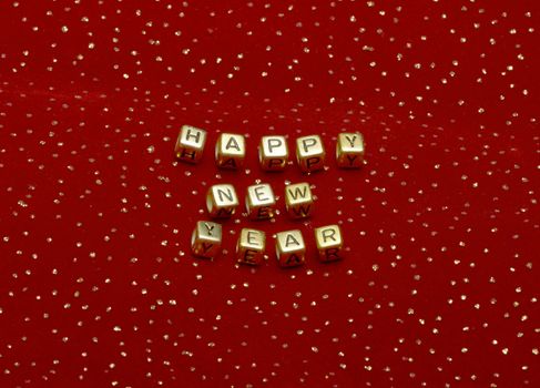photo of phrase "happy new year" of beads on a red velvet with sequins