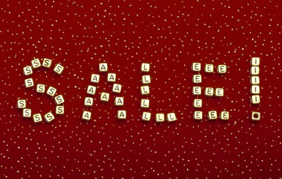 photo of word "SALE" of beads on a red velvet with sequins