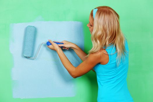 woman paints the wall roller