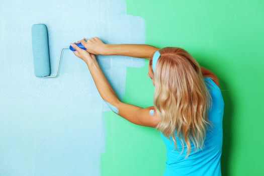 woman paints the wall roller