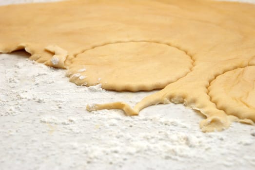 Detail of circles being cut from a sheet of fresh pastry with some shapes having already been removed