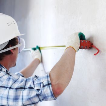 worker often with a measuring tape to the wall