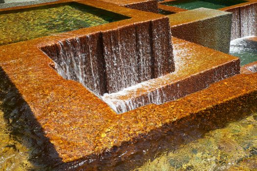 Multiple pools with water falls over golden concrete walls