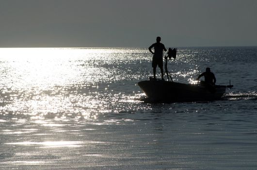 Boat sailing away at sundown