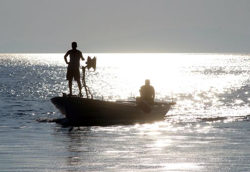 Boat sailing away at sundown