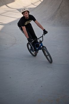 Teen boy rides a bicycle in the bike park .