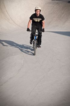 Teen boy rides a bicycle in the bike park .