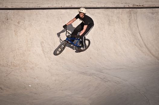 Teen boy rides a bicycle in the bike park .