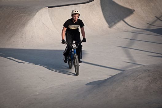 Teen boy rides a bicycle in the bike park .