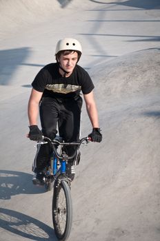 Teen boy rides a bicycle in the bike park .