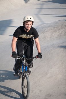 Teen boy rides a bicycle in the bike park .