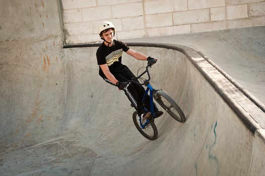 Teen boy rides a bicycle in the bike park .